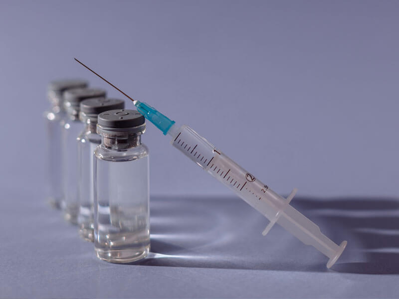 Four vials of peptide therapy and a syringe.