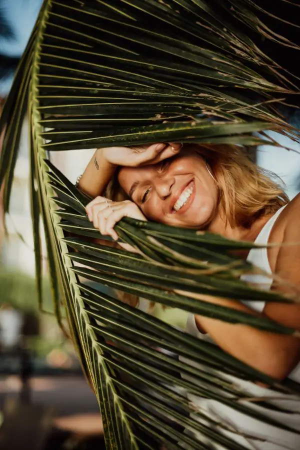 Woman with balanced gut health peeking out from behind a palm.